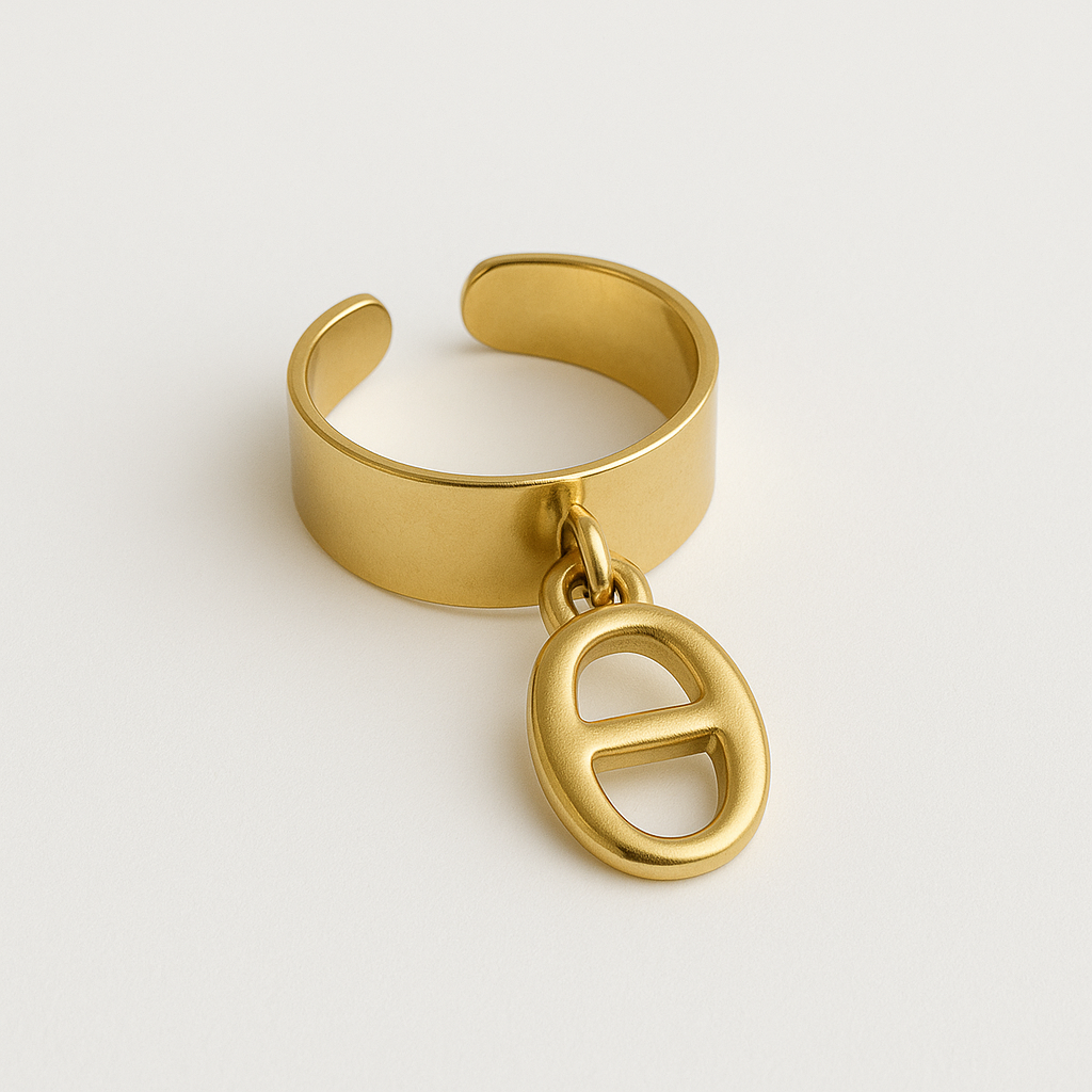 Bague dorée ajustable avec breloque ovale en métal affichant un motif "H", présentée sur fond blanc professionnel. La bague arbore une finition lisse et brillante, idéale pour un look élégant et sophistiqué. Parfait pour sublimer toutes les tenues avec une touche de raffinement.
