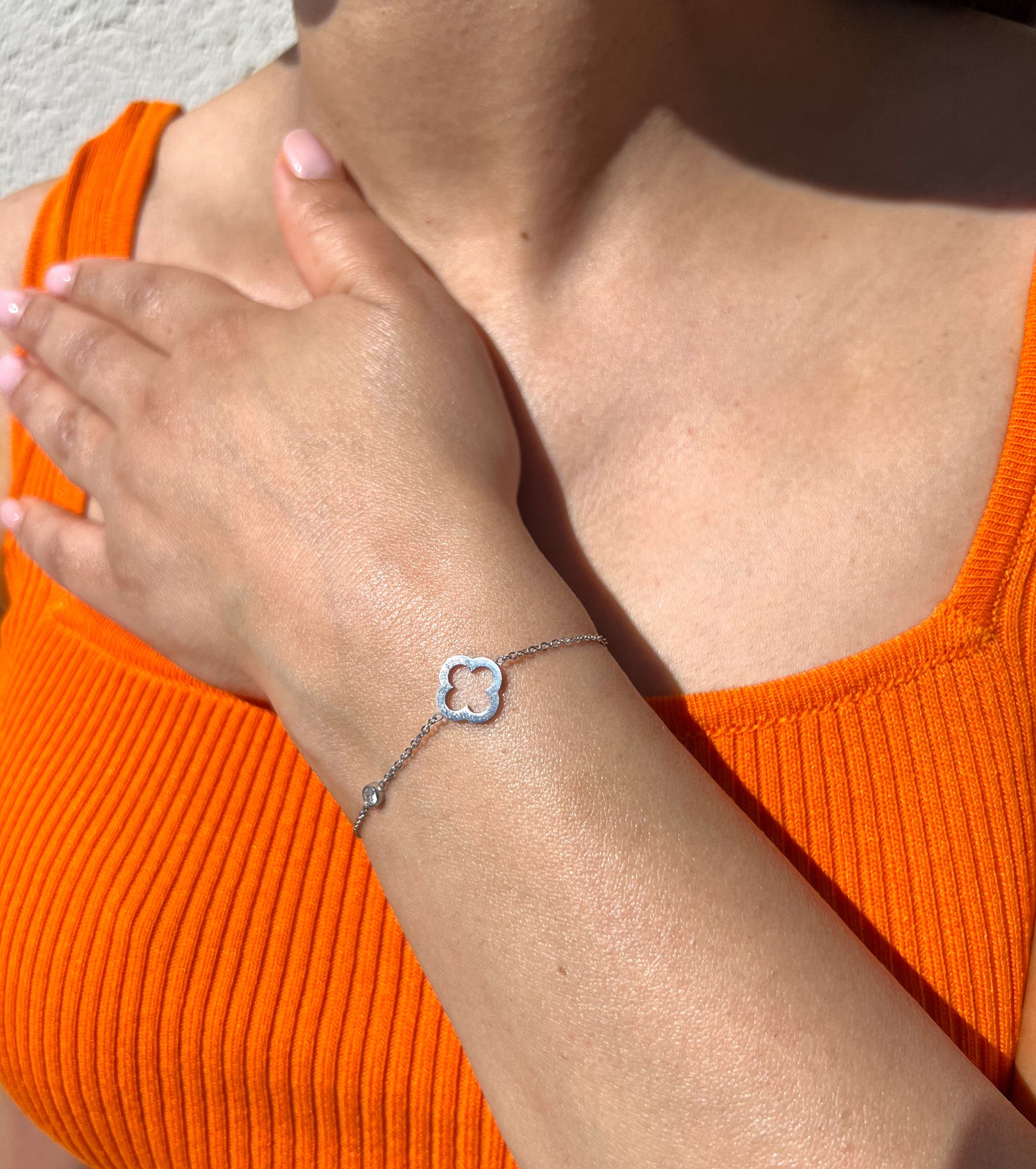 Bracelet en acier inoxydable argenté avec un pendentif trèfle orné de cristaux scintillants, porté sur un poignet féminin. Bijou élégant et raffiné de la collection Bisou Bijoux Paris.