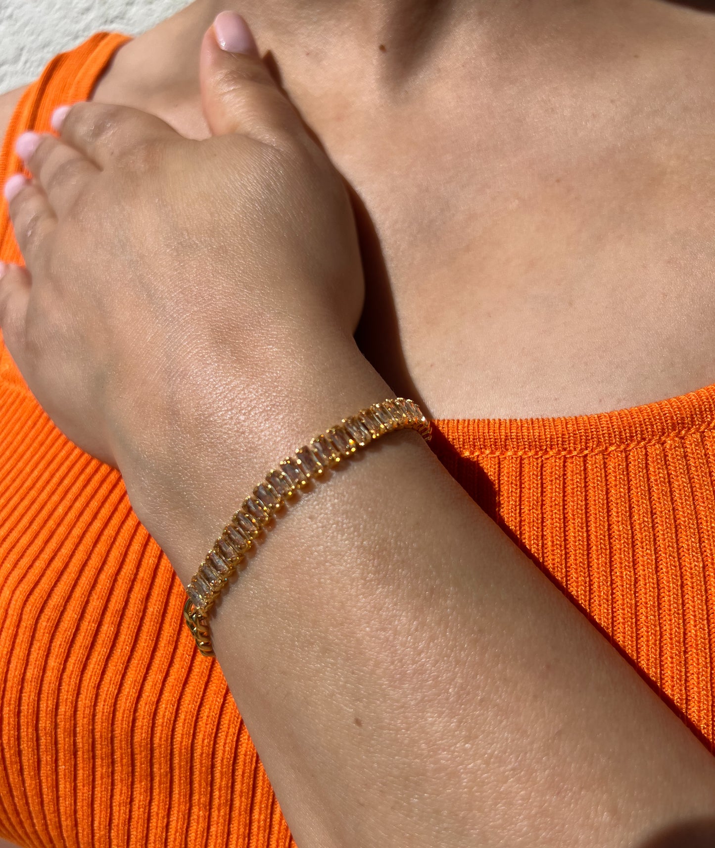 Bracelet en acier inoxydable doré orné de cristaux en forme de baguette, porté sur un poignet féminin. Bijou élégant et scintillant de la collection Bisou Bijoux Paris.