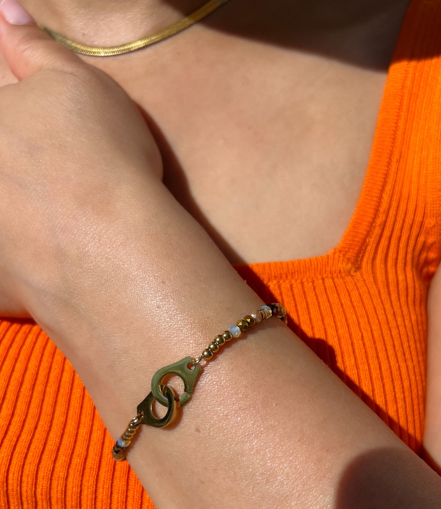 Bracelet en acier inoxydable doré avec maillons design et perles facettées, porté sur un poignet féminin avec un collier assorti. Bijou élégant et moderne de la collection Bisou Bijoux Paris.