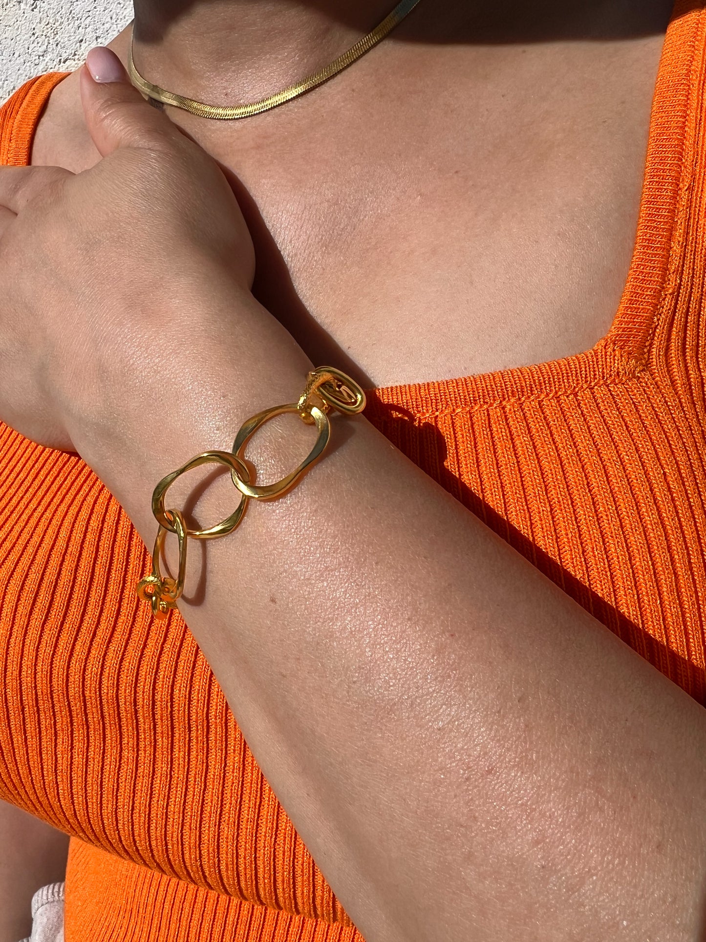 Bracelet en acier inoxydable doré avec grands maillons en chaîne, porté sur un poignet féminin avec un collier assorti. Bijou tendance et audacieux de la collection Bisou Bijoux Paris.