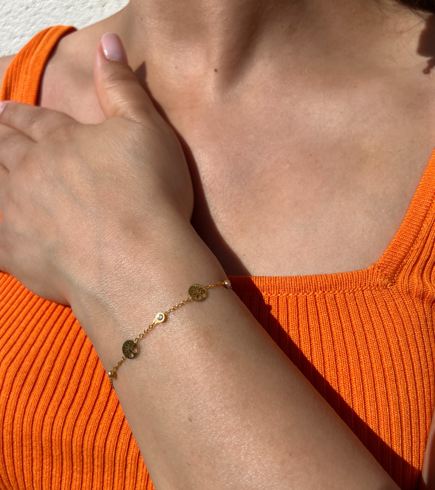 Bracelet en acier inoxydable doré avec pendentifs ronds "Arbre de Vie" et petite pierre incrustée, porté sur un poignet féminin. Bijou symbolique et élégant de la collection Bisou Bijoux Paris.