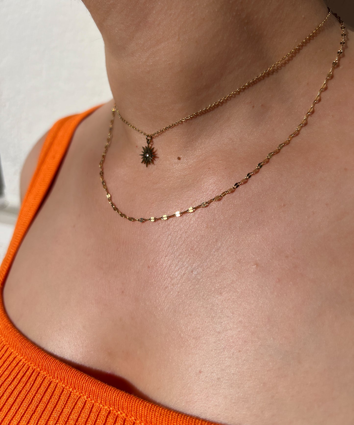 Collier double rang en acier inoxydable doré, avec un pendentif soleil et une fine chaîne perlée, porté autour du cou féminin. Bijou élégant et lumineux de la collection Bisou Bijoux Paris.