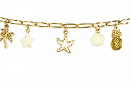 Détail du bracelet acier inoxydable charms tropical, avec breloques dorées en forme de palmier, étoile de mer, coquillage et ananas.
