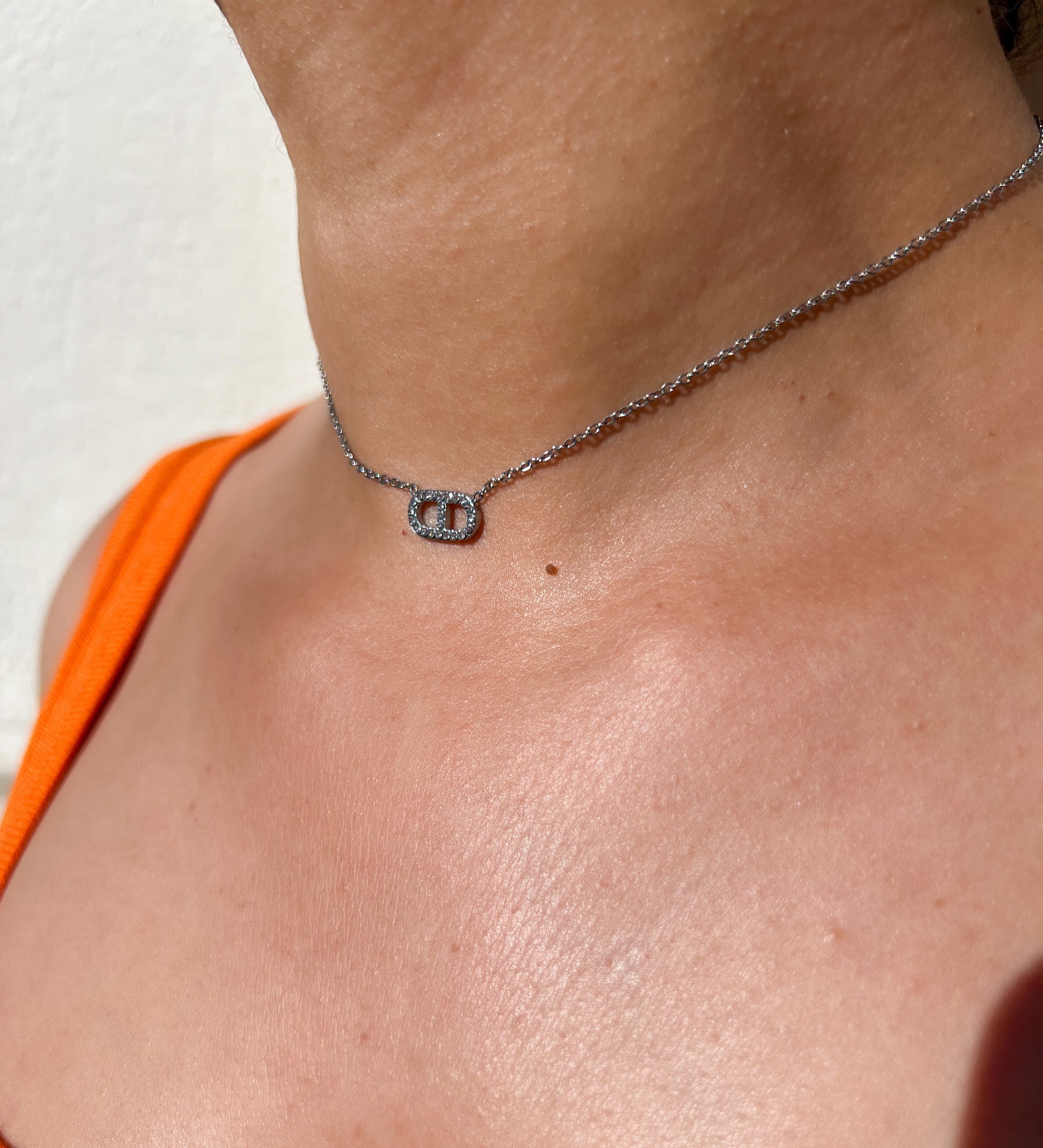 Collier en acier inoxydable argenté avec un pendentif double ovale serti de cristaux scintillants, porté autour du cou féminin. Bijou élégant et raffiné de la collection Bisou Bijoux Paris.