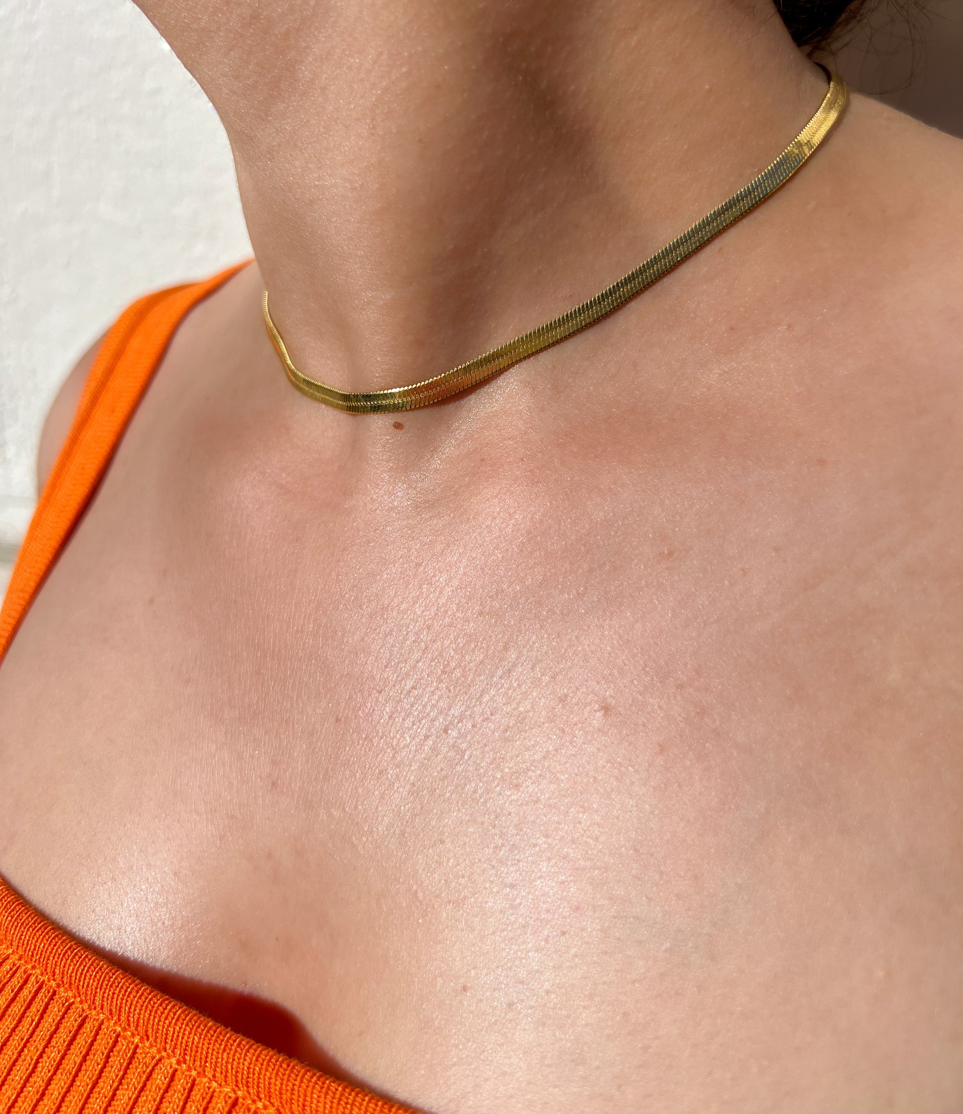 Collier en acier inoxydable doré avec une maille serpent, porté autour du cou féminin. Bijou élégant et intemporel de la collection Bisou Bijoux Paris.

