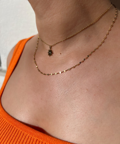 Collier double rang en acier inoxydable doré, avec un pendentif soleil et une fine chaîne perlée, porté autour du cou féminin. Bijou élégant et lumineux de la collection Bisou Bijoux Paris.